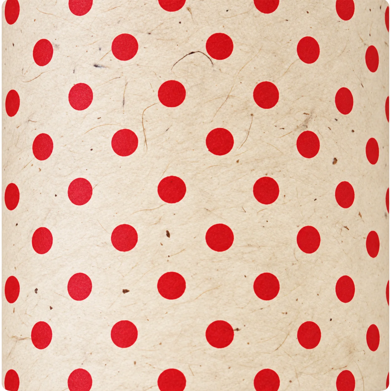 Gros plan sur un papier fait main de couleur crème, texturé de fibres, orné de pois rouges disposés en rangées régulières.