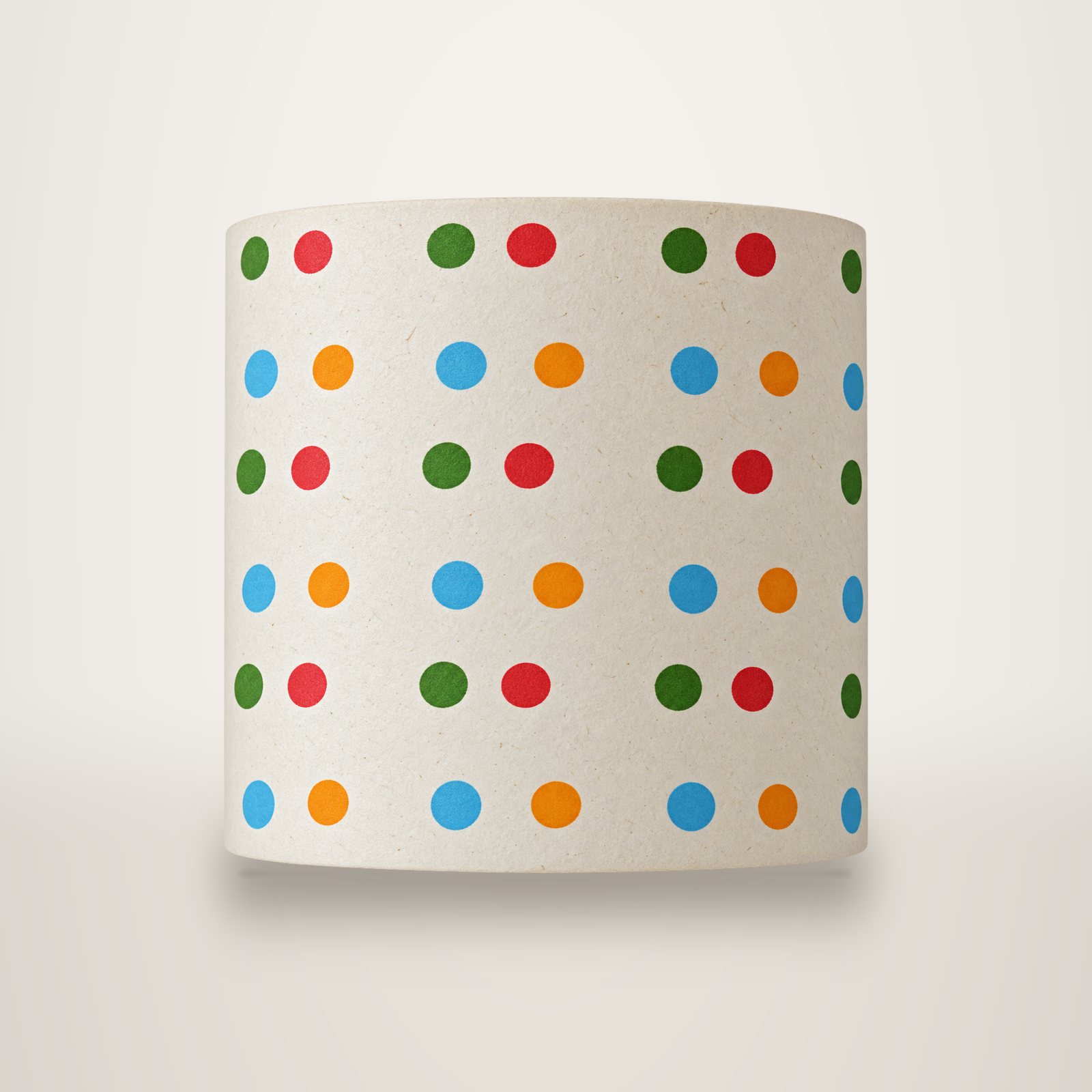 Gros plan sur un papier crème légèrement texturé orné de rangées de pois verts, rouges, bleus et orange.
